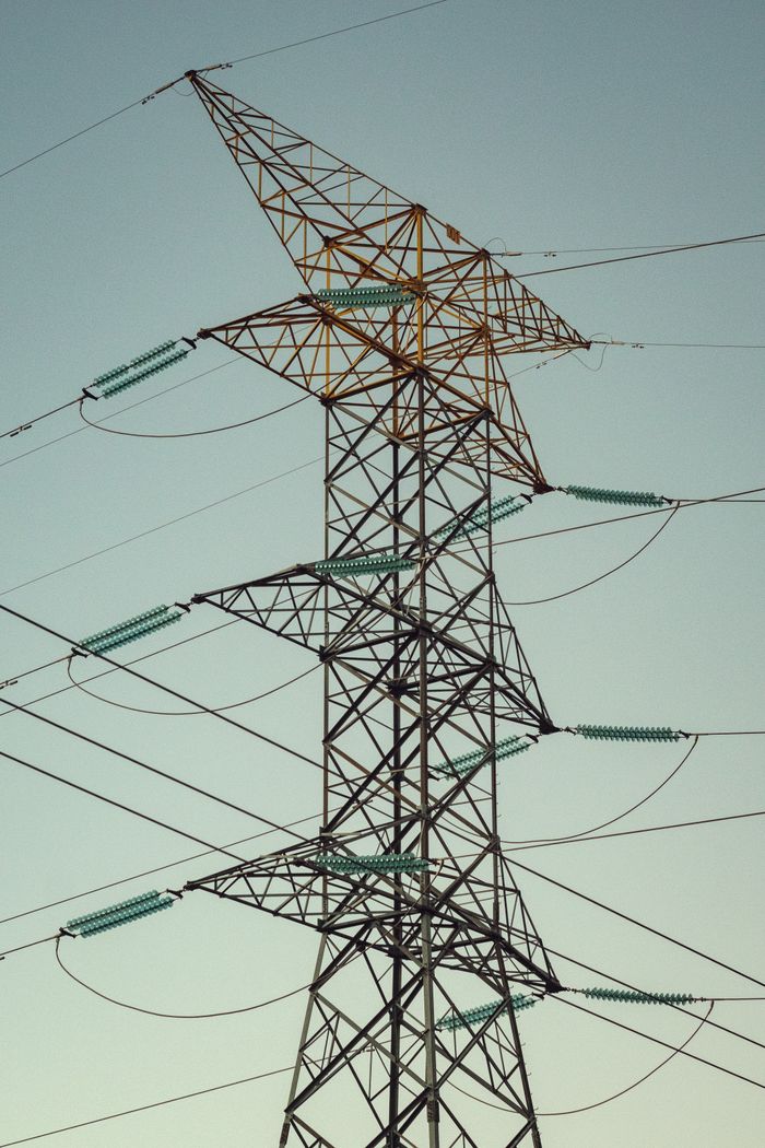 our-stories A tall electricity transmission tower standing against a clear sky, showcasing power and engineering.